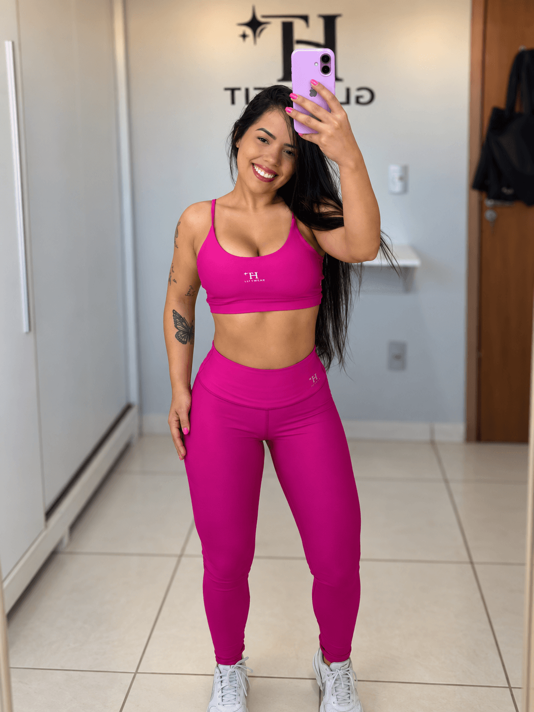 Modelo de Conjunto Neide fúcsia fazendo foto no espelho da loja
